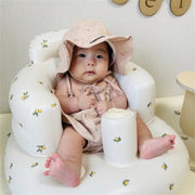 Baby in pink outfit and sun hat seated in floral baby chair, Kid Zone educational toys