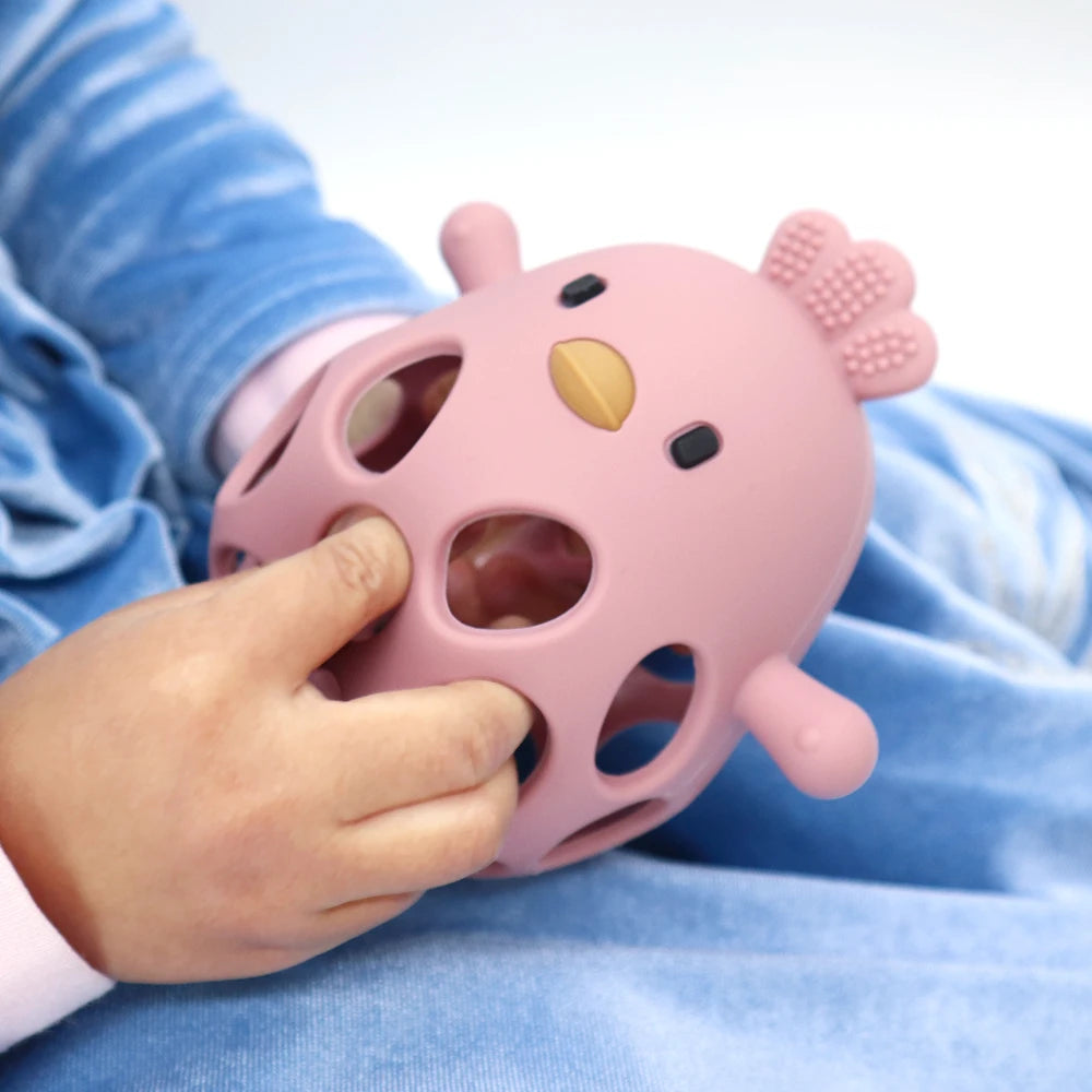 Baby holding pink chicken-shaped sensory toy, educational baby toy for learning and play