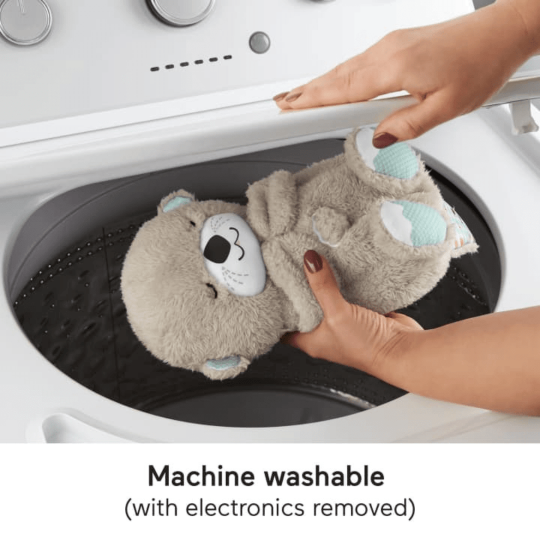 Hands placing a plush otter calming toy for babies into a washing machine, machine washable.