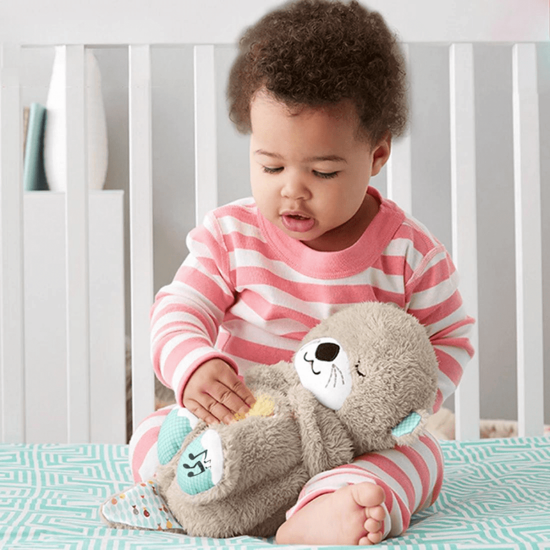 Toddler in pink striped pajamas holds a plush otter calming toy in a crib, baby essentials.
